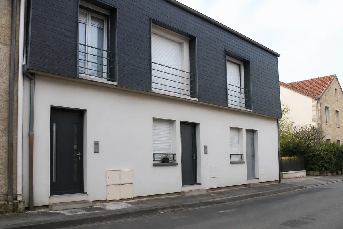 Façade d&rsquo;une maison de ville divisée en trois logements, avec compteurs et interphone