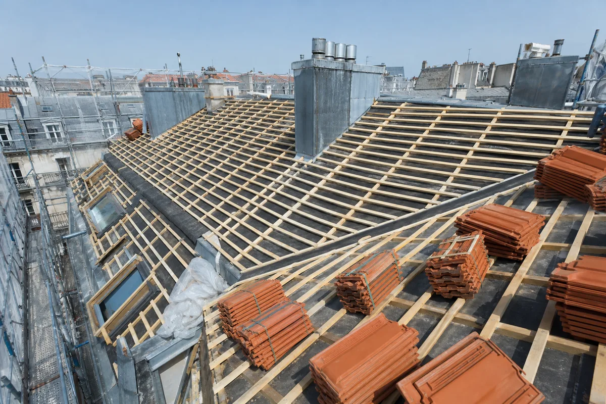 Toiture d’immeuble collectif en cours de réfection avec échafaudage et tuiles neuves